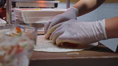 Doner kebap yapıyorum. Bir adam et ve sebzeleri lavaşla sarar..