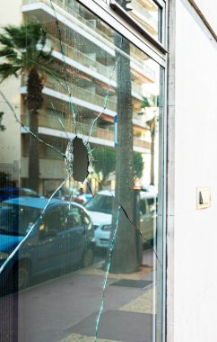 Broken glass in a store on the street. Vandalism and theft concept. clipart