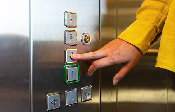 Woman pressing button inside elevator.