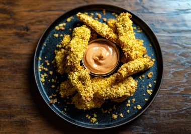 Altın kabuklu ve soslu çıtır tavuk şeritleri..