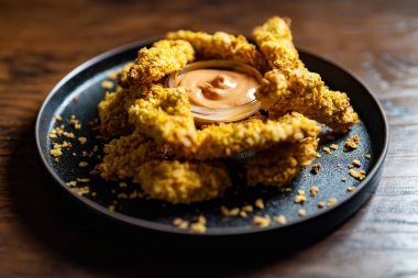 Altın kabuklu ve soslu çıtır tavuk şeritleri..