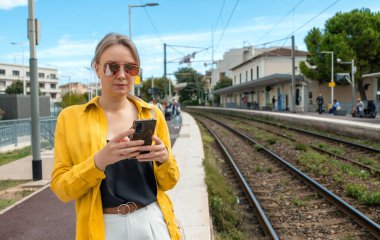 Akıllı telefonlu bir kadın trenini bekliyor..