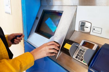 Bir kadın bilet makinesinden tren bileti alıyor..