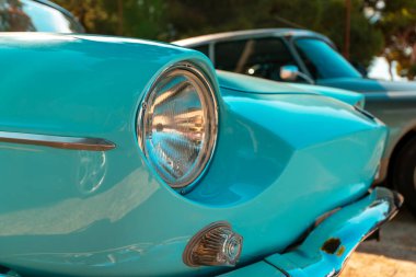 Parlak farları ve krom detayları olan klasik turkuaz araba..