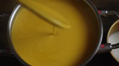 Tencerede kabak çorbası. Tahta kaşıkla karıştırıyor.