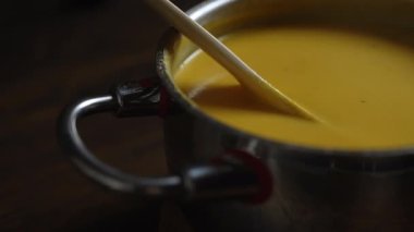 Tencerede kabak çorbası. Tahta kaşıkla karıştırıyor.