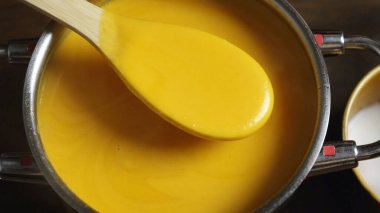 Tencerede kabak çorbası. Tahta kaşıkla karıştırıyor.