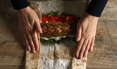 Wrapping shawarma in lavash with chicken and vegetables. clipart