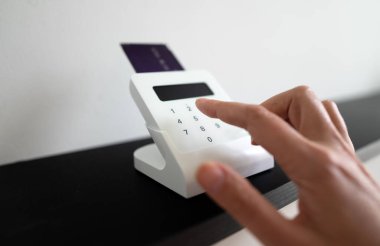 Kadının eli kablosuz ödeme terminaline PIN kodu giriyor.