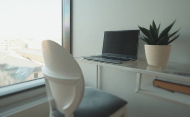 Ofis çalışma alanındaki pencerenin yanındaki dizüstü bilgisayar..