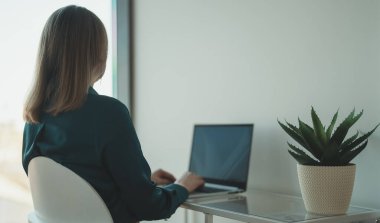 Ofiste dizüstü bilgisayarla çalışan bir kadın..