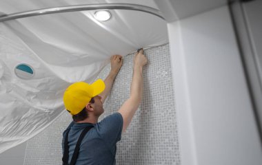 Bir adam banyonun esnek tavanını söküyor..