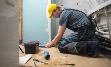 Tuvalette boru döşeyen bir adam var..