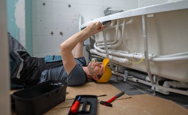 Adam banyo küvetinin boru sistemine su masajı yapıyor..