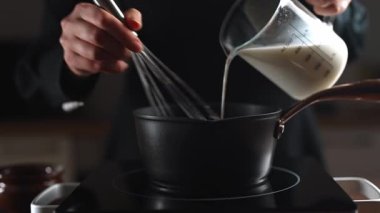 Kadın aşçı beşamel sosu hazırlıyor, kasede karıştırıyor..