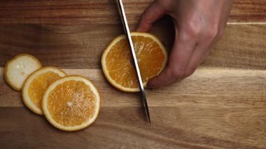 Mutfak bıçağıyla taze portakal dilimleyen bir kadın..