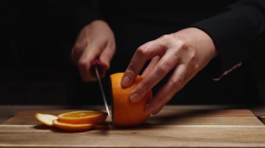 Mutfak bıçağıyla taze portakal dilimleyen bir kadın..