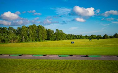 Mavi güneşli gökyüzünün altında yeşil golf sahası.