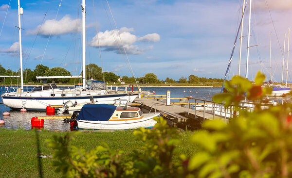 Парусники и моторные лодки пришвартованы на спокойной пристани.