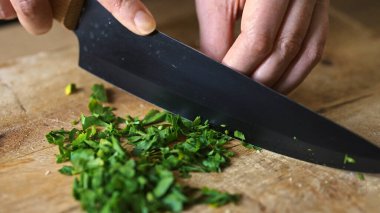 Tahta kesme tahtasıyla taze maydanoz doğrama.