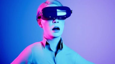 Teknoloji, online oyun, eğlence, sanal dünya üç boyutlu simülasyon. VR gözlüklü bin yıllık kadın Neon Stüdyosunda oynuyor..