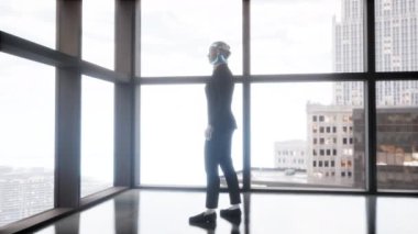 Boş ofiste kalan ve pencereden büyük şehre bakan bir insansı robot. gelecek teknoloji konsepti.
