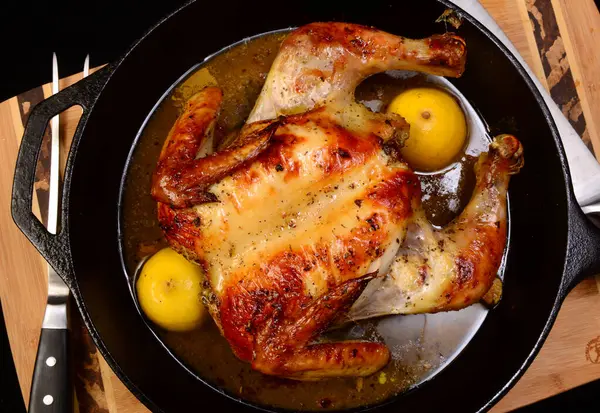 Whole chicken that has been spatchcocked roasted in a cast iron skillet with a lemon, olive oil, and oregano sauce.