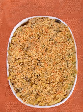 Fırından yeni çıkmış hindili tetrazzini güvecinin portakal rengi bir minderin üzerinde dinlenme görüntüsü.