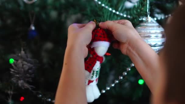 雪だるまの形をしたおもちゃで人工のクリスマスツリーを飾る子供の手 休日の準備の雰囲気 — ストック動画