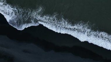 Dron perspektifinden çekilen okyanus dalgalarının hava panoramik görüntüleri. İzlanda, kumlu siyah plaj.