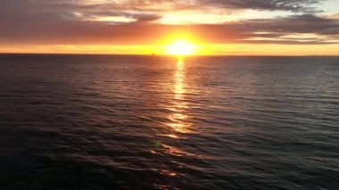 Aerial panoramic footage of ocean waves in sunset with cruiser on background. Beautiful sunset landscape with horizon.