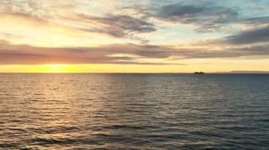 Aerial panoramic footage of ocean waves in sunset with cruiser on background. Beautiful sunset landscape with horizon.