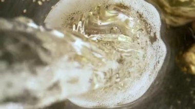 Kameranın hareketinin çok yavaş bir şekilde şampanya kadehine dönüşmesi. Kutlama ve başarı kavramı. Yüksek hızlı sinema kamerası, 1000fps.