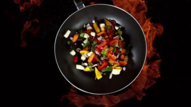 Ateşli tavadan dilimlenmiş sebze parçalarının süper yavaş çekimleri. Yüksek hızlı sinema kamerası, 1000 fps. Hız rampası etkisi.