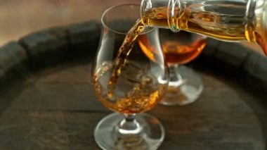 Süper yavaş çekimde konyak bardağa hızlı çekimle dökülüyor. Yüksek hızlı sinema kamerası, 1000 fps, yüksek hızlı sinüs robotuna yerleştirilmiş. Hız rampası etkisi.