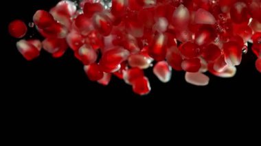 Nar parçalarının suya düşmesi çok yavaş bir hareket. Siyah arka planda izole edilmiş. Yüksek hızlı sinema kamerası, 1000fps