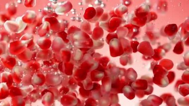 Nar parçalarının suya düşmesi çok yavaş bir hareket. Kırmızı arka planda izole edilmiş. Yüksek hızlı sinema kamerasıyla çekildi, 1000fps. Hız rampası etkisi.