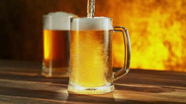 Glass of light beer pouring on wooden table. Studio shot with isolated glass of beer.