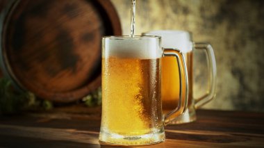 Glass of light beer pouring on wooden table. Still life shot with wooden keg on background.