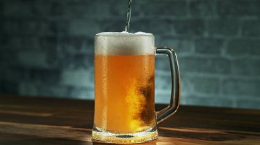 Glass of light beer pouring on wooden table. Studio shot with isolated glass of beer.