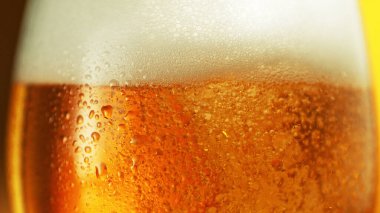 Water drops with beer bubbles in glass, close-up. Extreme detail shot focused on glass.