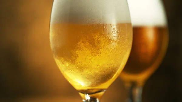 Glass of light beer on dark golden background. Isolated glass of beer, macro shot.