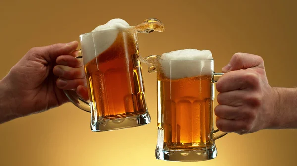 Two Glasses Beer Cheers Gesture Splashing Out Isolated Golden Background — Fotografia de Stock