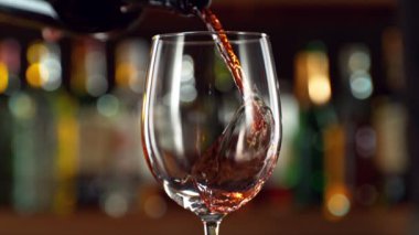 Super slow motion of pouring red wine into goblet. Bar with bottles on background. Filmed on high speed cinema camera, 1000fps.