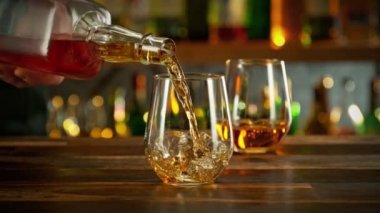 Super slow motion of pouring whisky into glass with speed motion. Filmed on high speed cinema camera, 1000 fps, placed on high speed cine bot. Bar with bottles on background.
