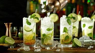Preparation of mojito drinks on bar counter. Fresh beverages background.