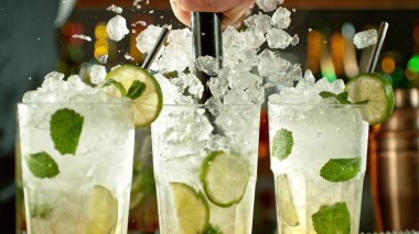 Preparation of mojito drinks on bar counter. Fresh beverages background.