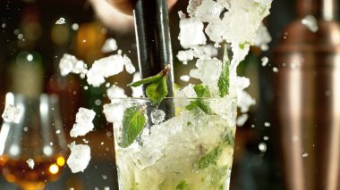 Preparation of mojito drink on bar counter. Fresh beverages background.