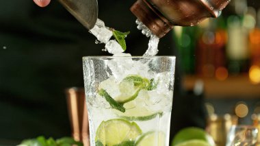 Preparation of mojito drink on bar counter. Fresh beverages background.