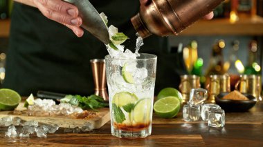 Preparation of mojito drink on bar counter. Fresh beverages background.